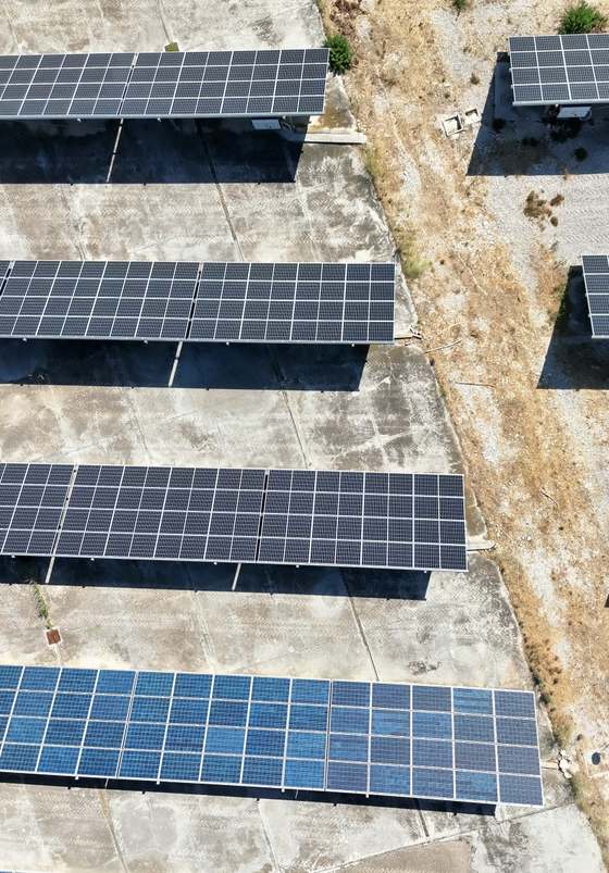 Ripresa aerea di moduli fotovoltaici su platea in cemento e terreno